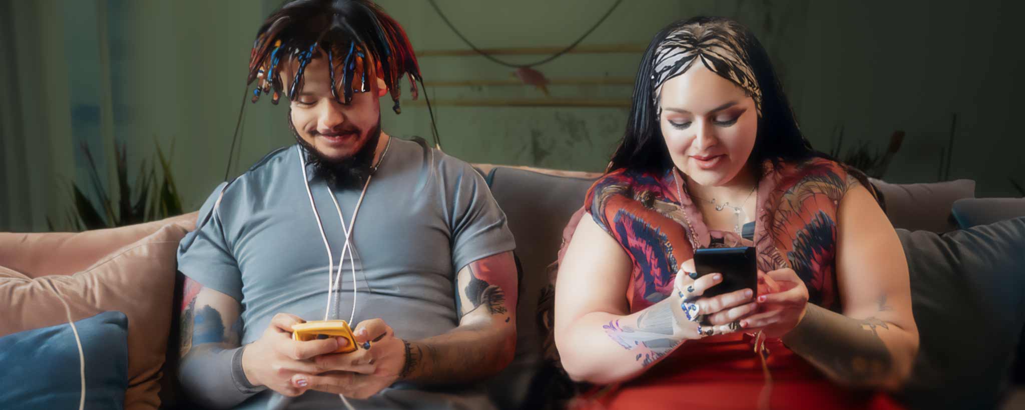 'A tattooed couple using digital devices on the sofa. (ai)'