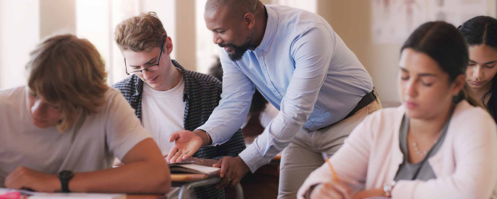 'Teacher assisting students in a classroom setting.'