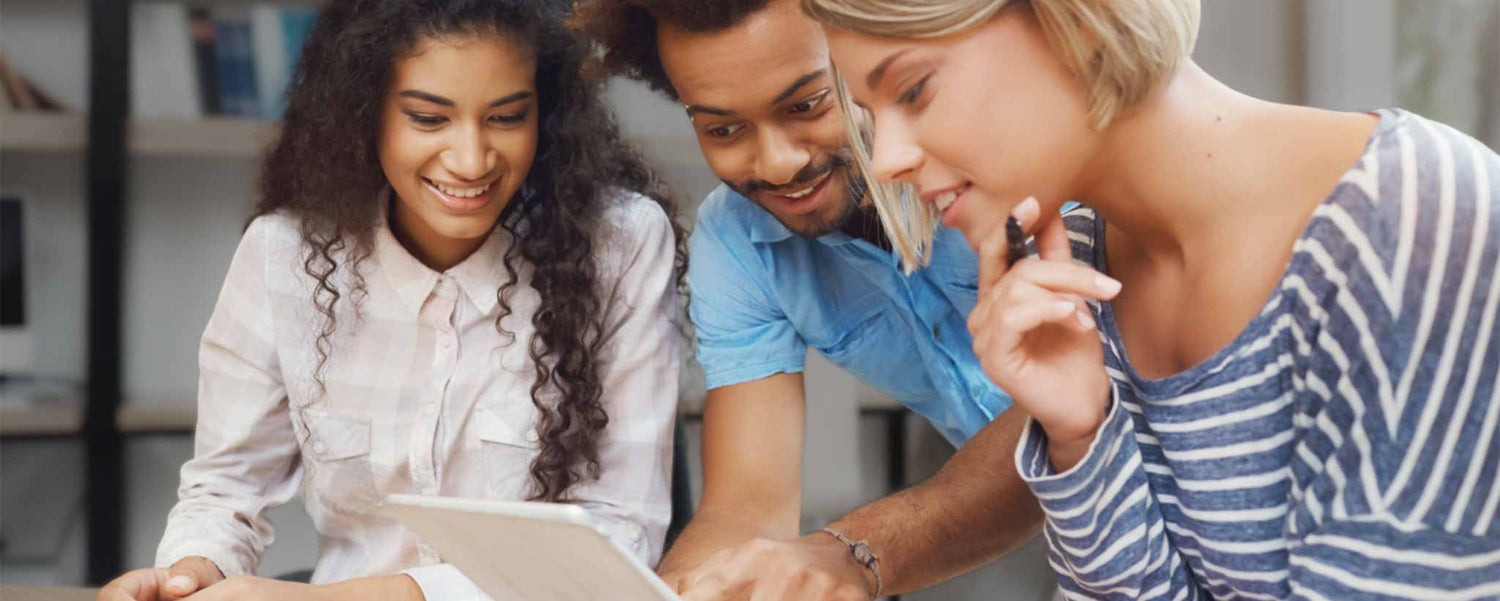 Three people are looking at a tablet together in an indoor setting.