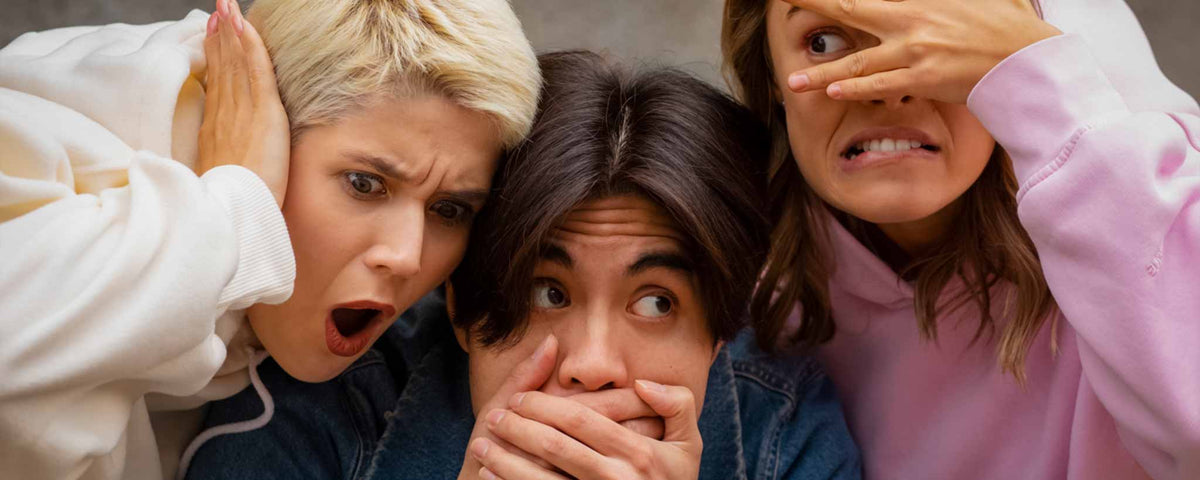 'Three surprised young adults, covering their ears, eyes, and mouths.'