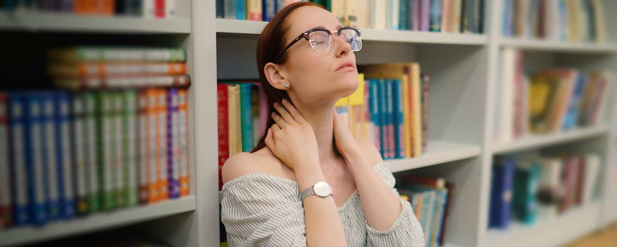 'Lady holding neck on library floor'