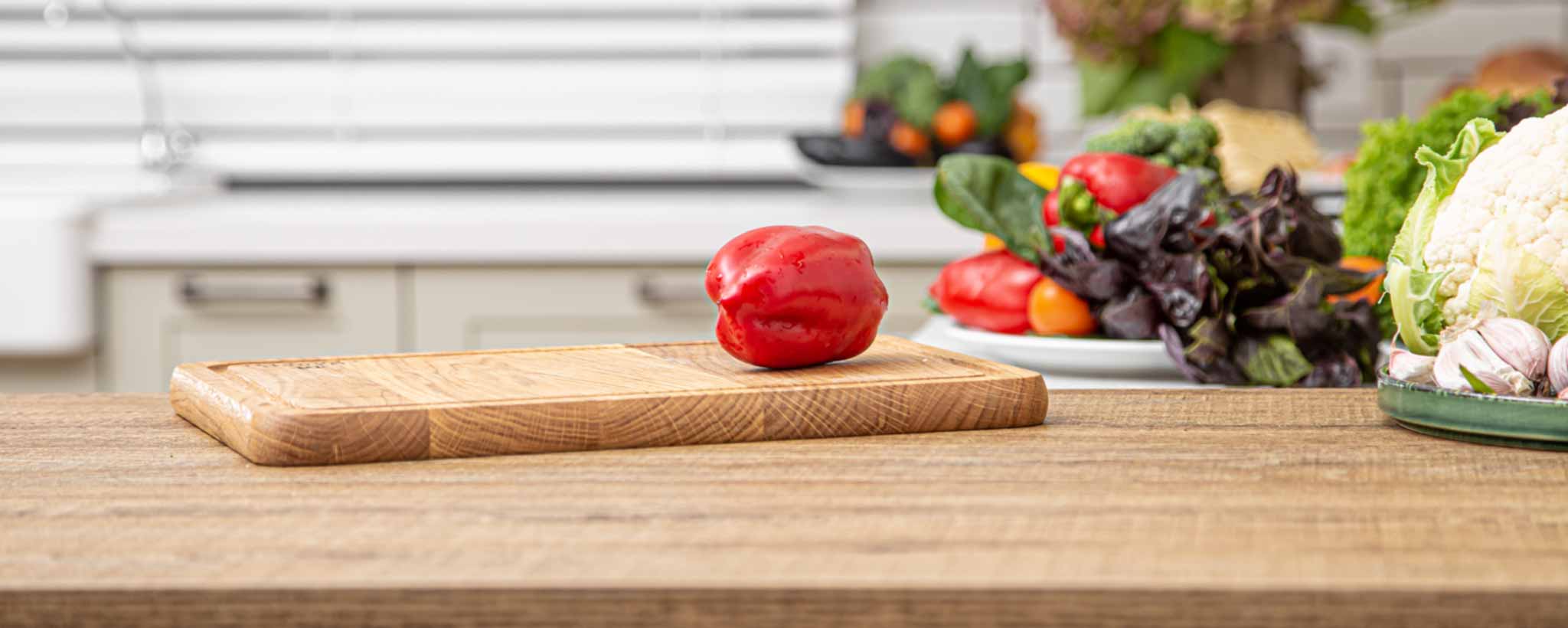 'A wooden cutting board with vegetables on a kitchen counter.'