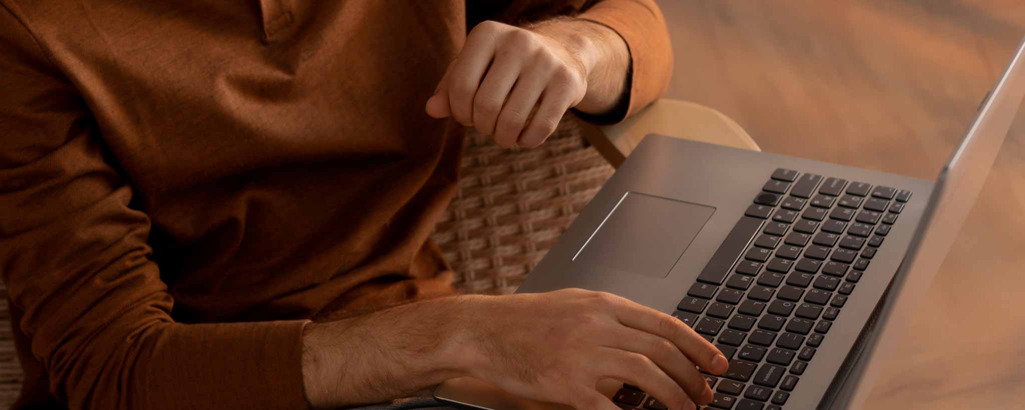 'A man's hands using a laptop computer.'