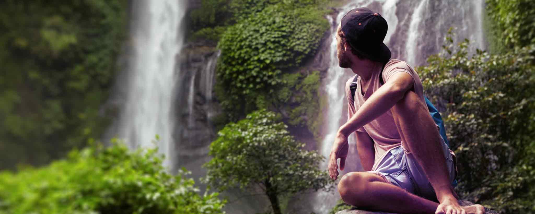 'A man seated by a waterfall.'