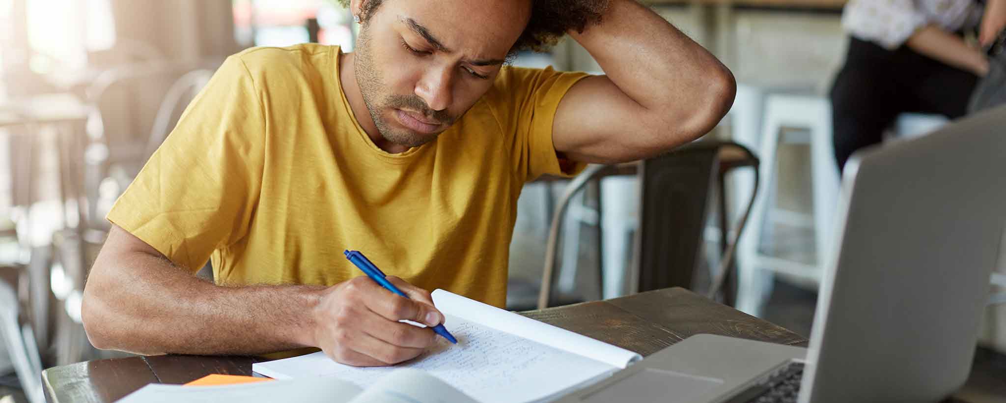 'Man writing in coffee shop'