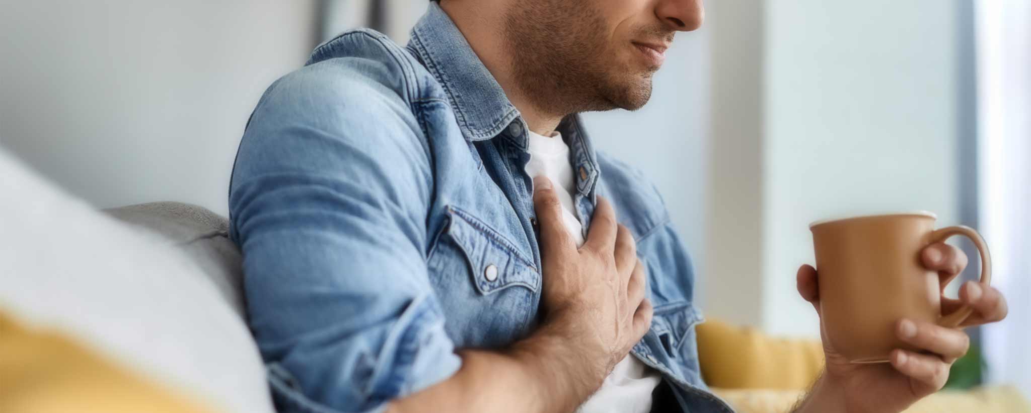 'Man with coffee cup holding his chest'