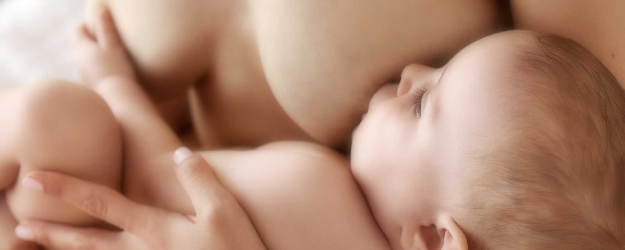 A topless mother breastfeeds her baby.