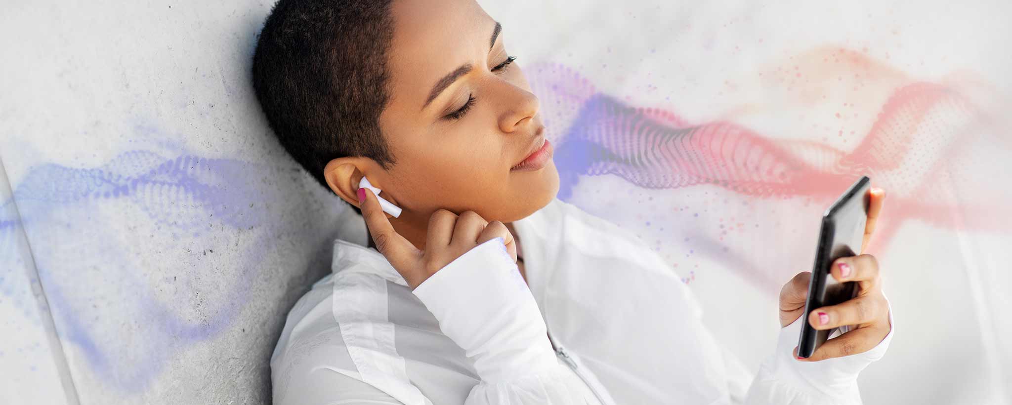 'A lady is listening to AirPods while holding her phone.'