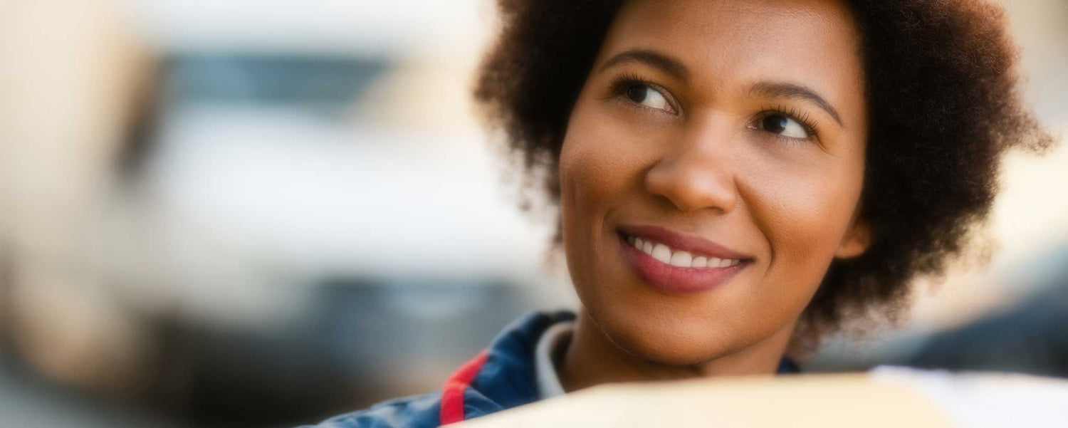 A smiling black female postal carrier.