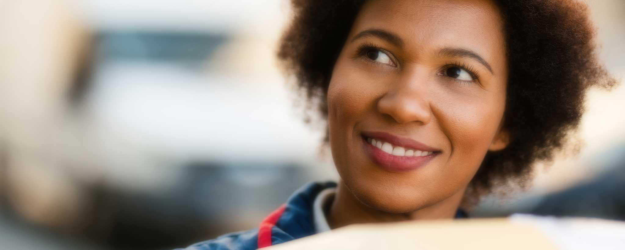 A smiling black female postal carrier.