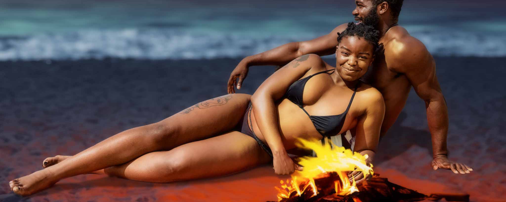 'A Belizean couple recline on the beach near a campfire.'
