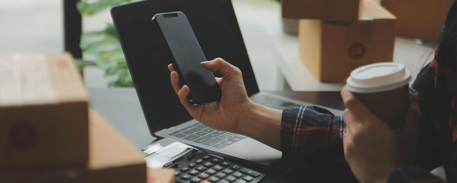 Hand holding phone with boxes on a table