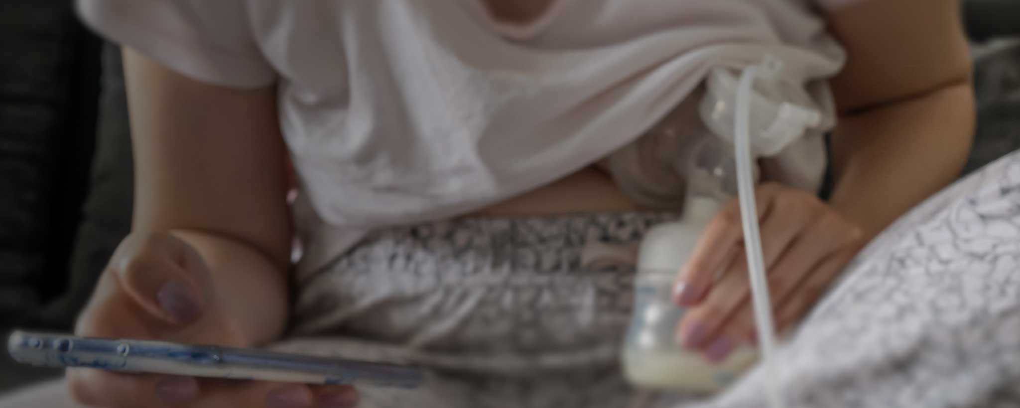 'A mother is pumping her breast milk while wearing pajamas.'