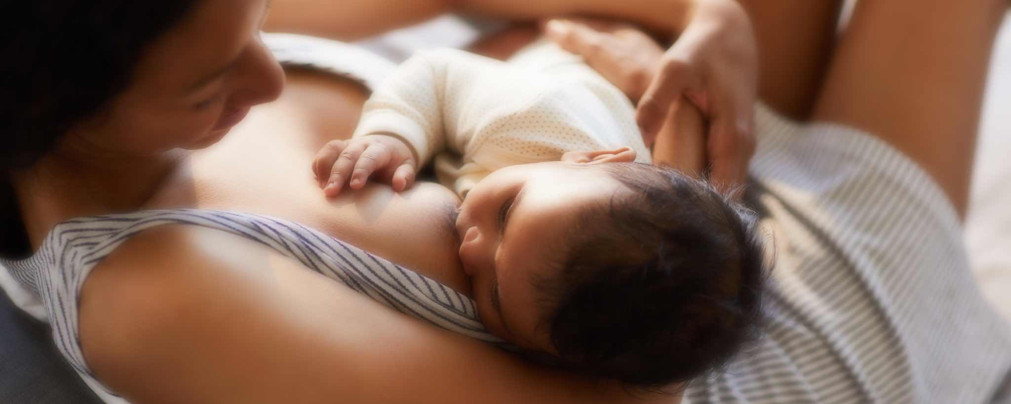 Reclining mother breastfeeding infant.