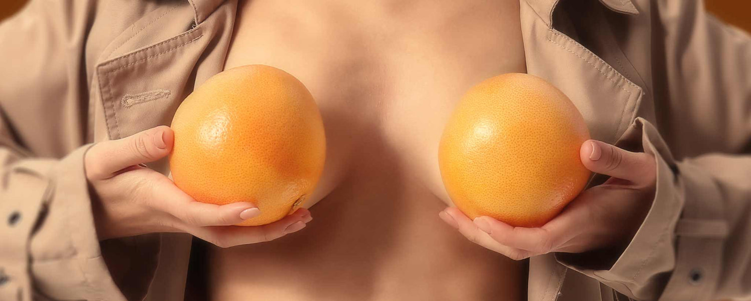 Female holding grapefruits in front of breasts