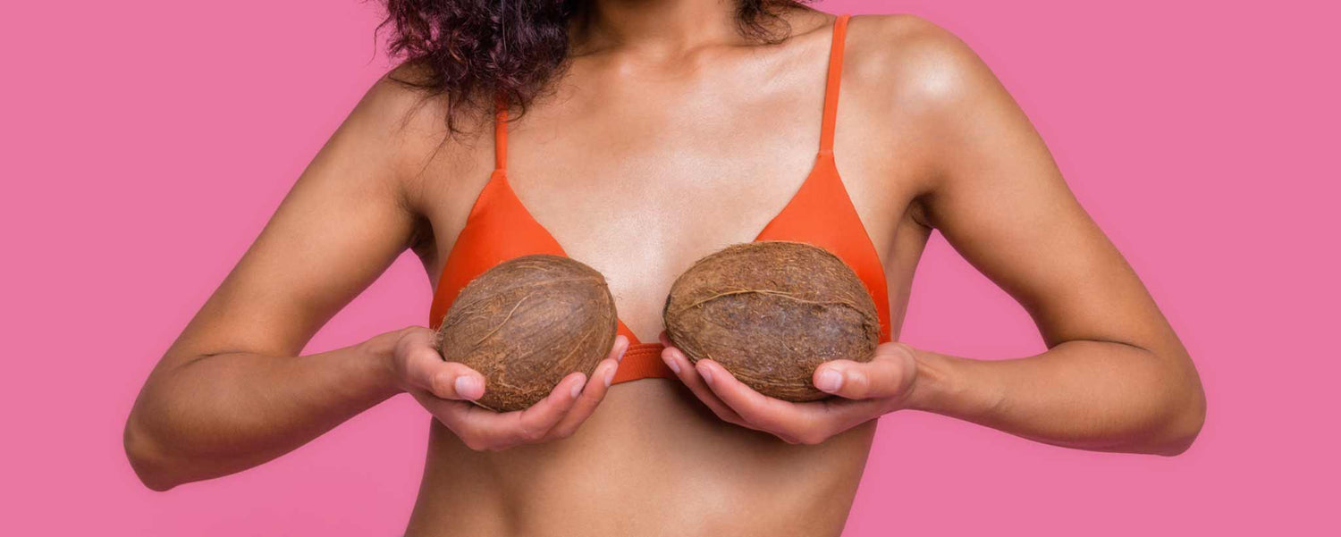 Female holding coconuts in front of breasts