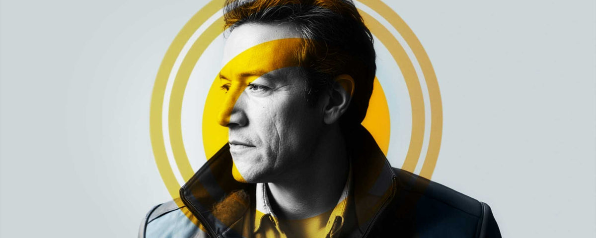 A black and white portrait of Fadi H. Kacem in profile wearing a dark jacket over a yellow shirt, with a large yellow circular graphic behind him on a light gray background.