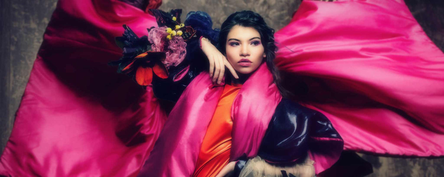An exotic female fashion model wears a magenta gown.