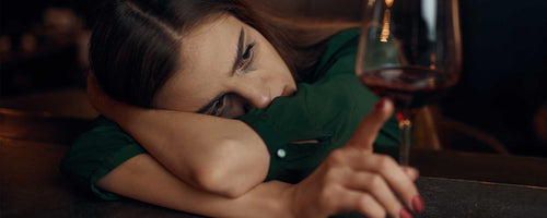 Depressed female at bar with alcohol glass