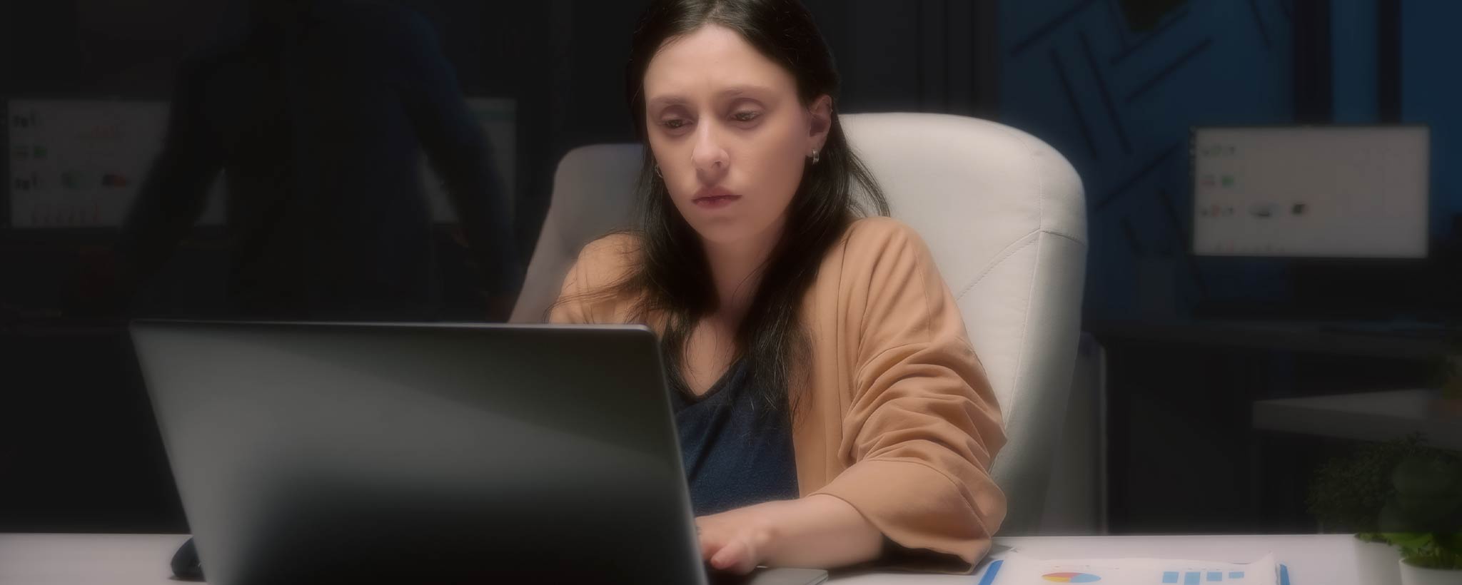 'Female typing on desk laptop computer at night'