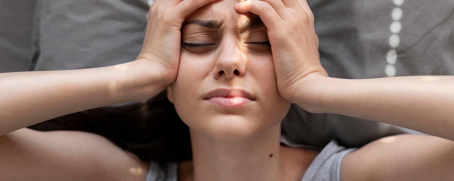 Female lying on pillow holding her head