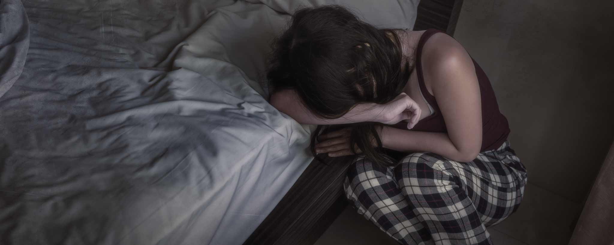 'A crying woman crouches by her bed.'