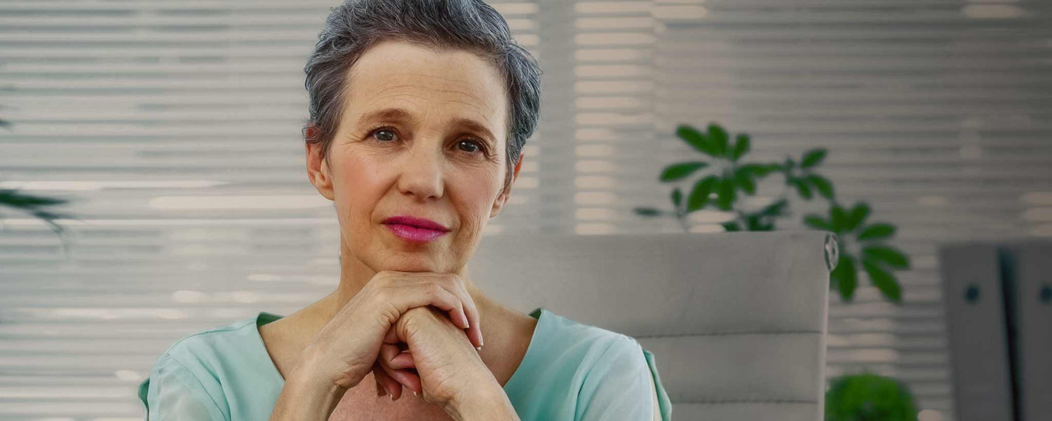 A serious female counselor office clasps her hands behind her desk.