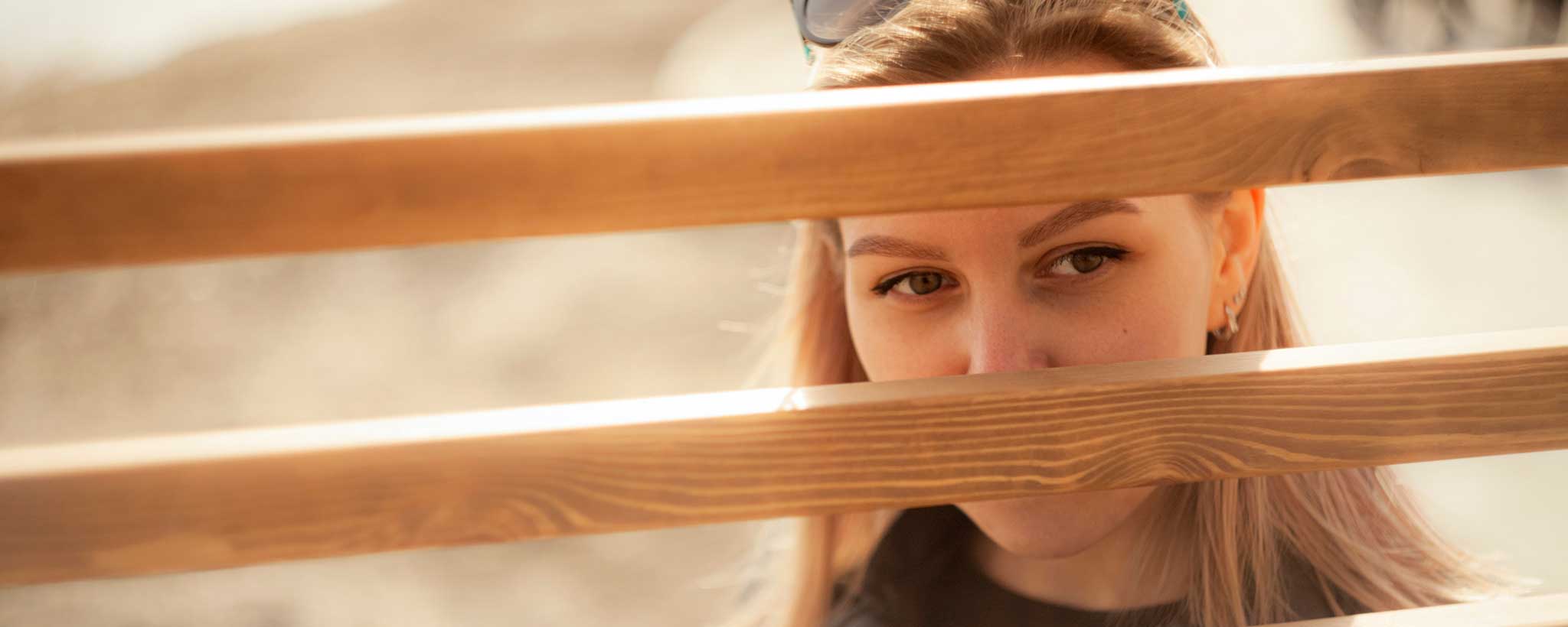 'Blonde woman peeking through fence'