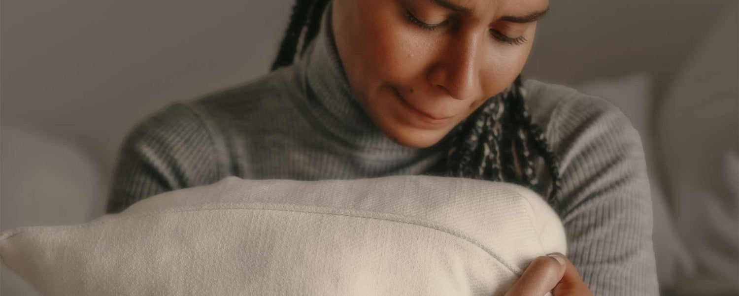 An anguished female squeezes her pillow.