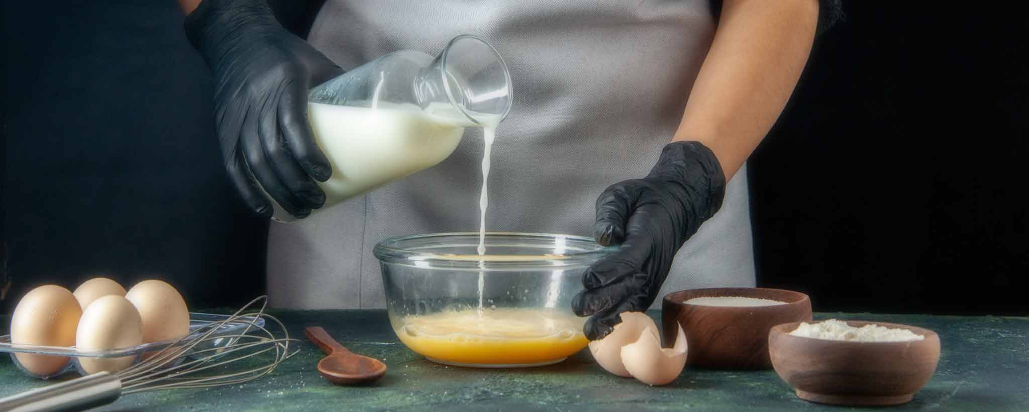 'A lady pours milk into a bowl.'
