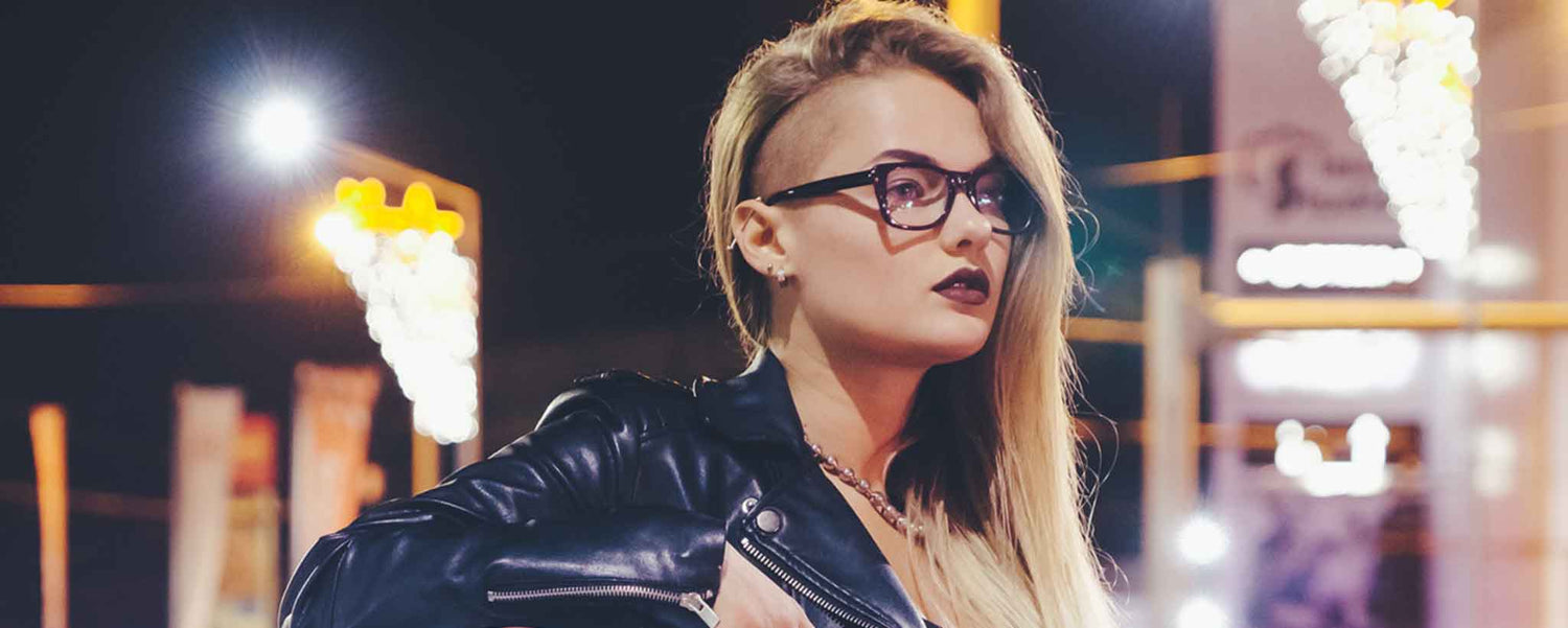 A young female punk-rocker stands in the evening streetlights.