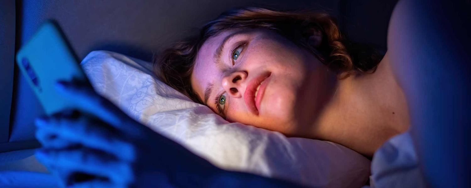 Female lying in bed with smartphone