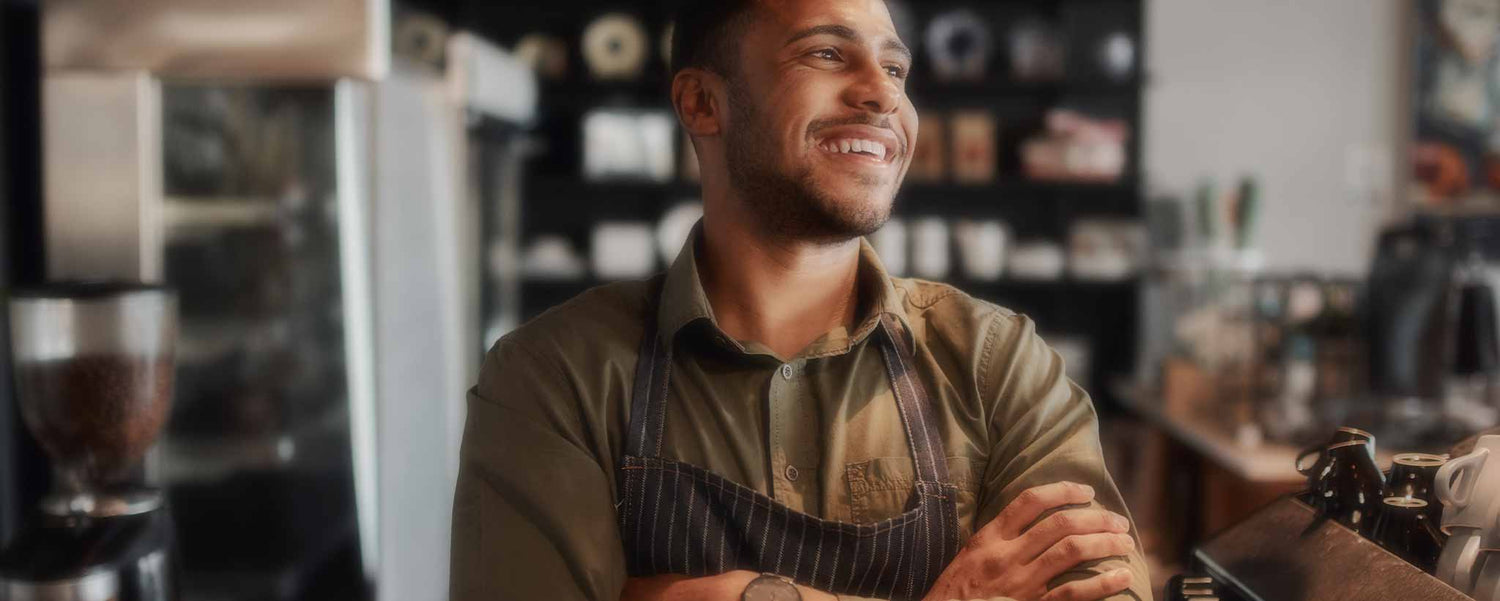 A handsome black male barista standing with his arms folded. (ai)