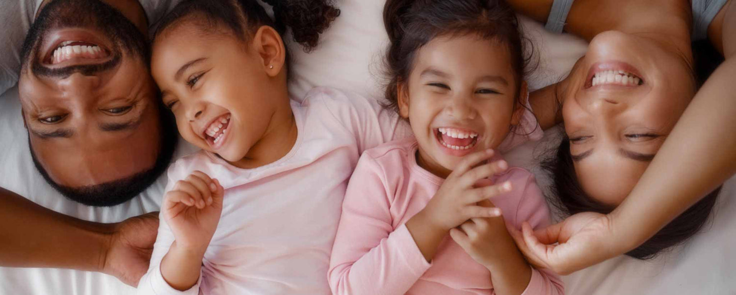 Happy girls with their parents lie in bed.