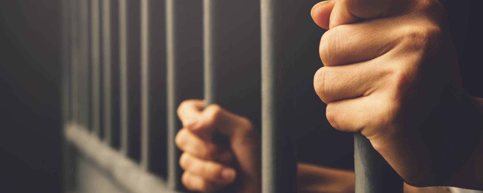 'Hands of prisoner behind bars'