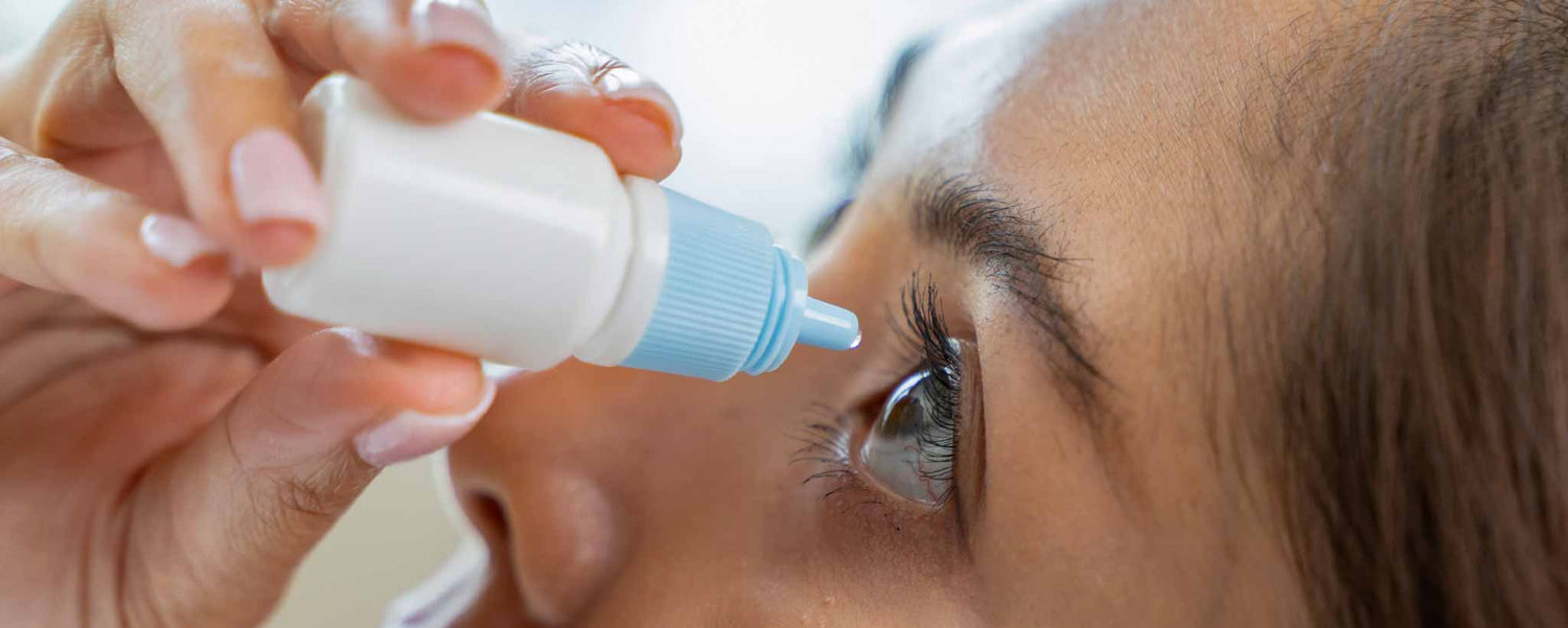 Close-up view of a lady applying eye drops.