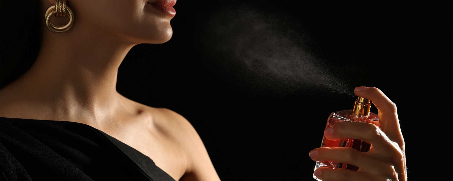 A lady spraying perfume with a dark background.