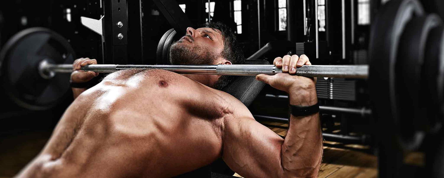 A strong man bench presses in a gym.