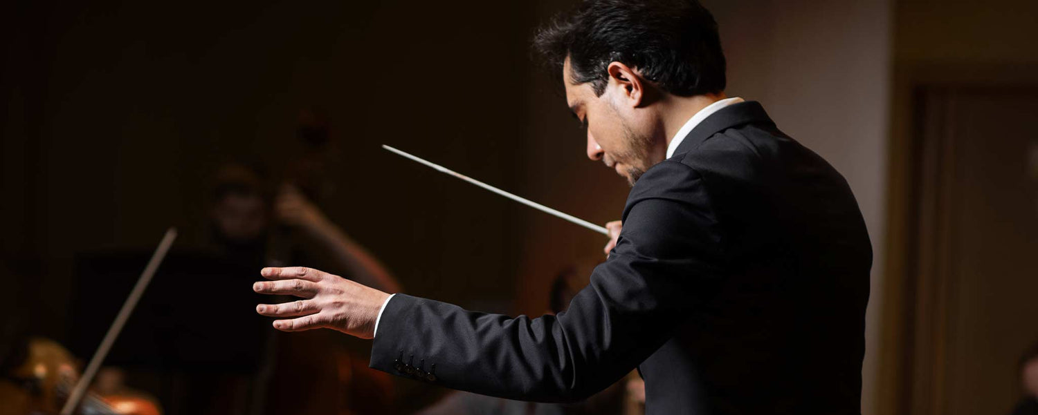 A male orchestra conductor waves his baton.