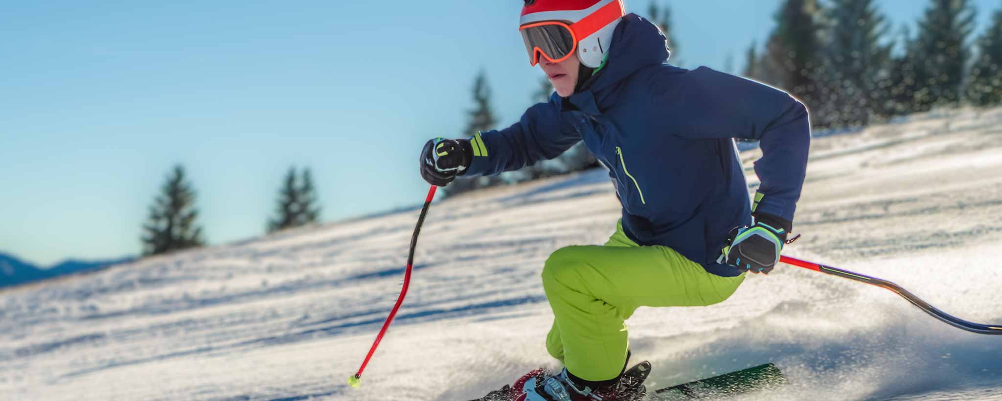 'A person skiing downhill on a snowy slope with trees in the background.'