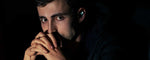 Man sits in darkness wearing a glowing earbud.