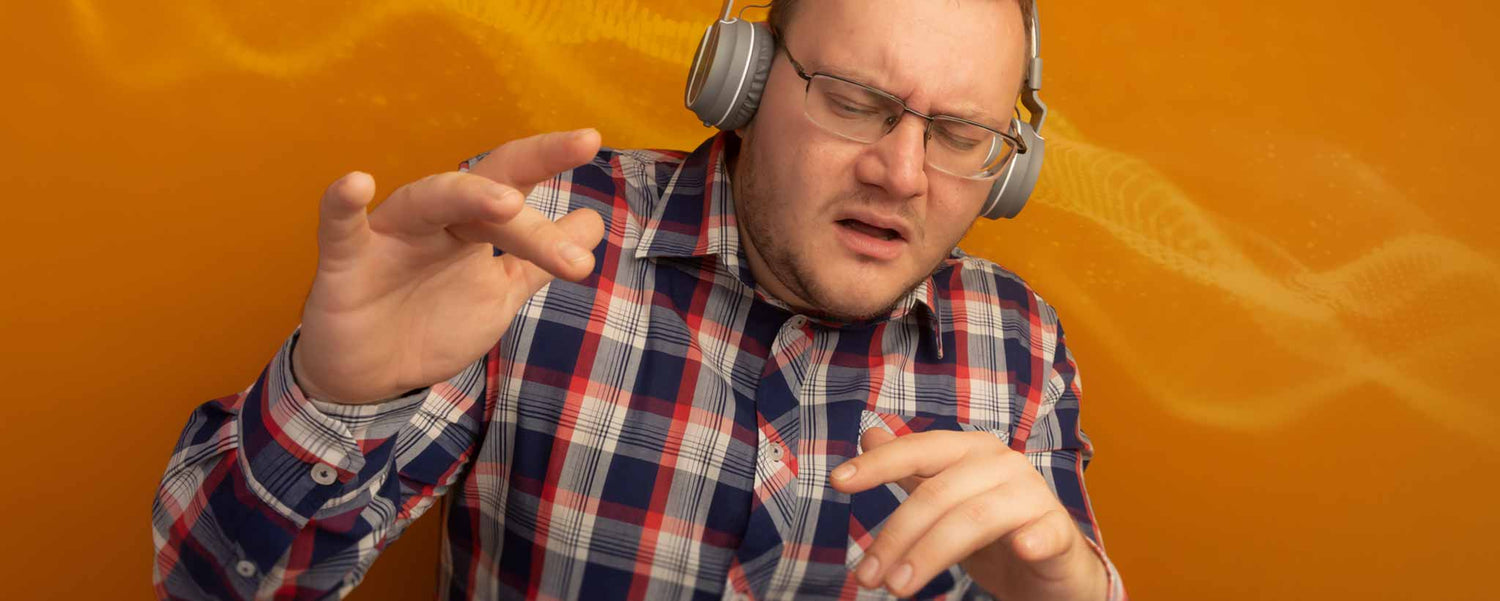 A man wearing headphones and a plaid shirt against an orange background.