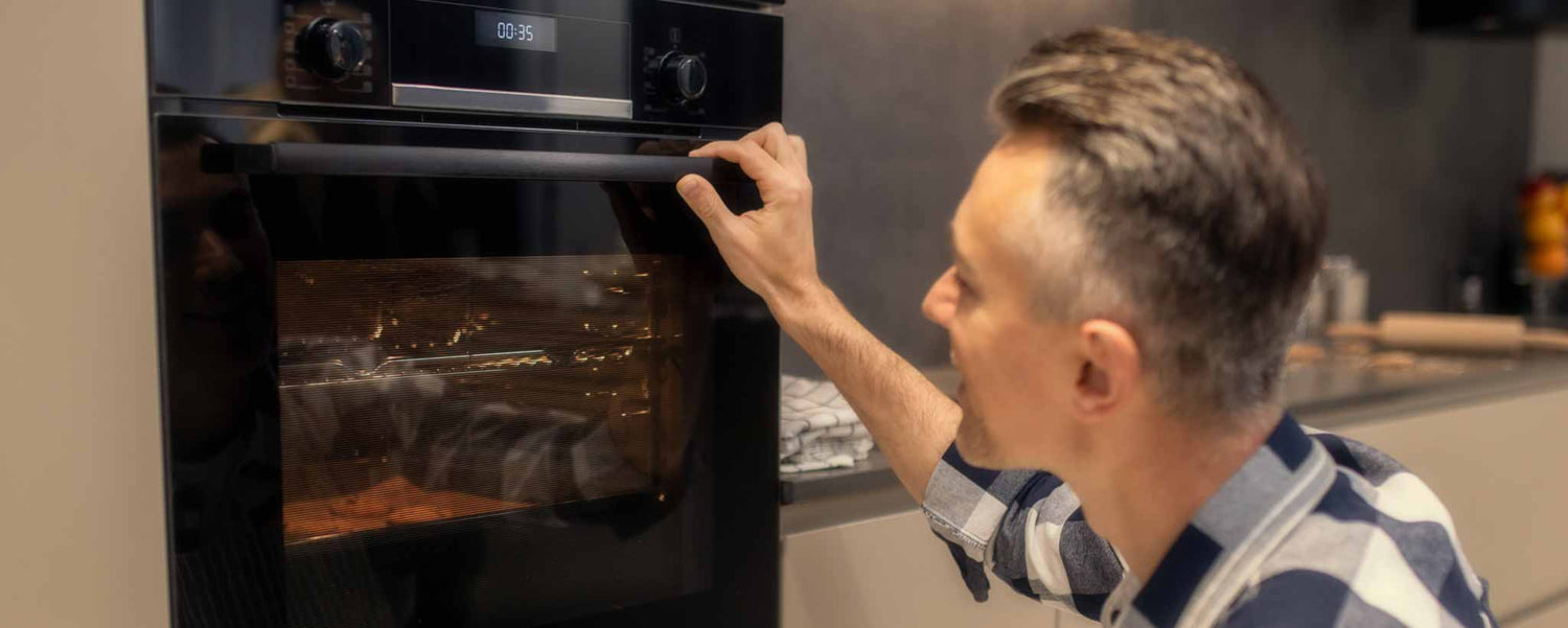 Man watching food cook in oven