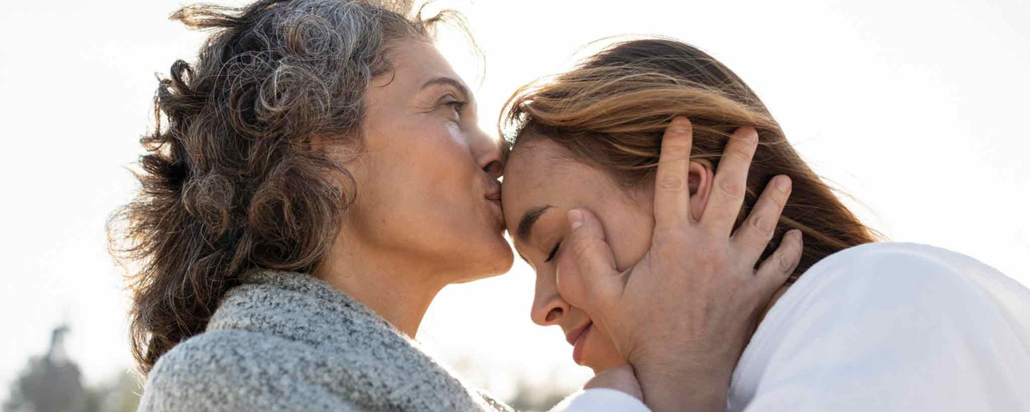 Mother kissing teen forehead