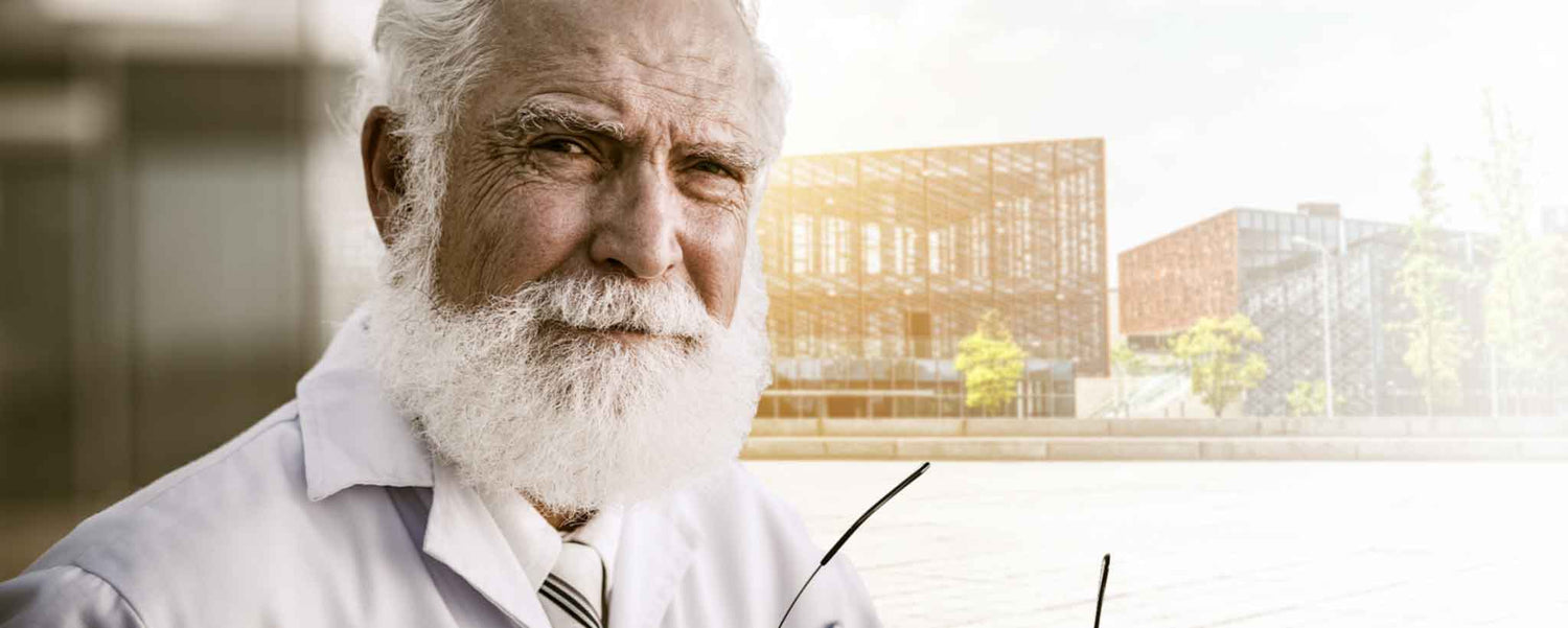 An aged bearded man with architectural drawings.