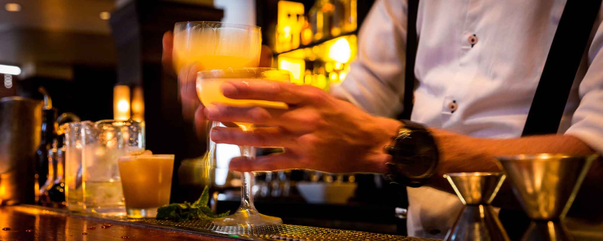 'Mixologists pouring drinks at bar'