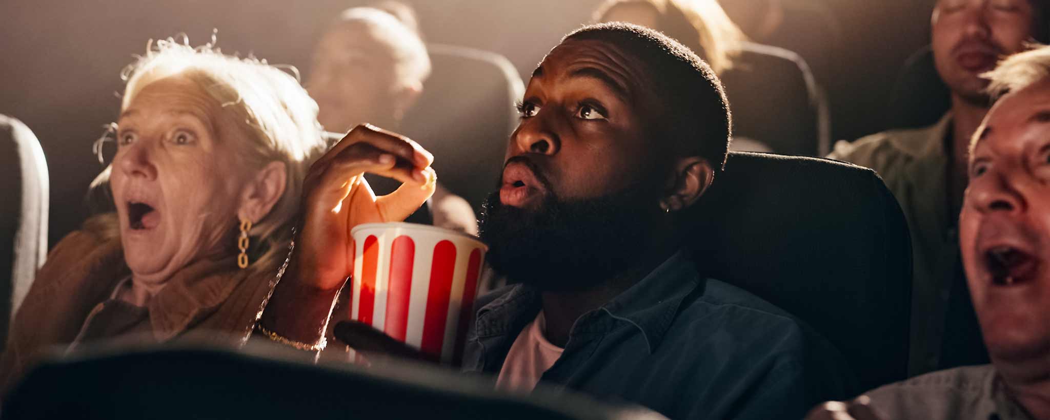 'Fearful people are watching a movie in a theater with popcorn.'