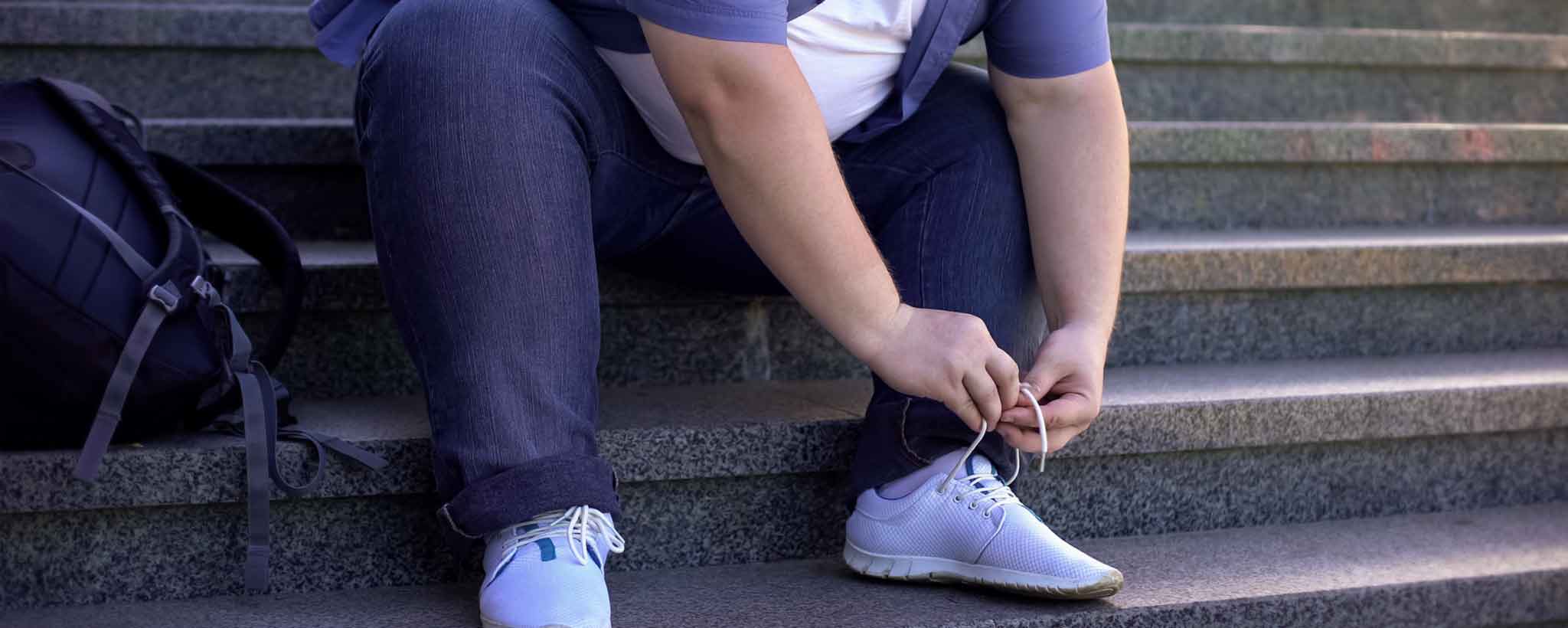 'Obese man tying shoes'