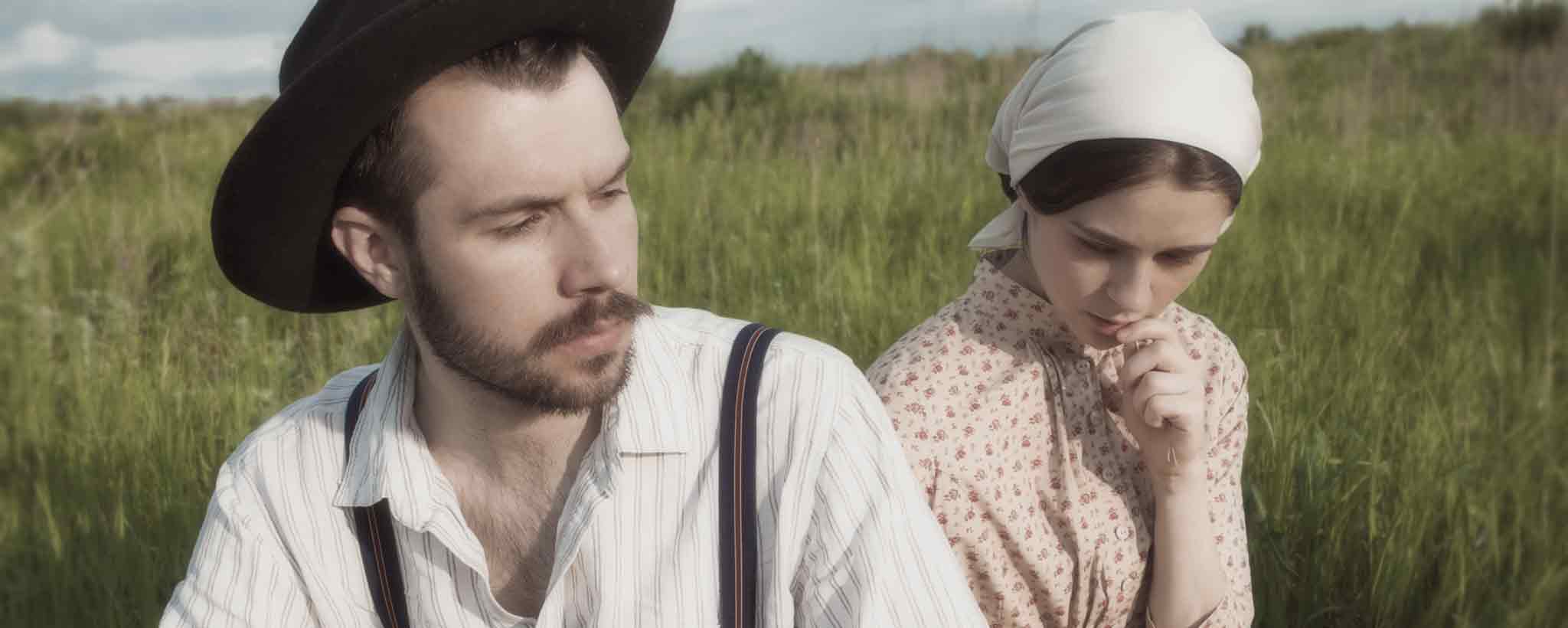 'A married couple in a rural field.'