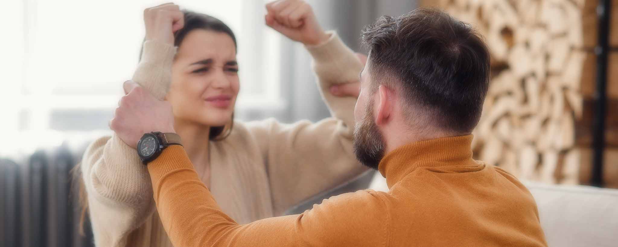 'A husband grabs his angry wife's arms during couple's therapy.'